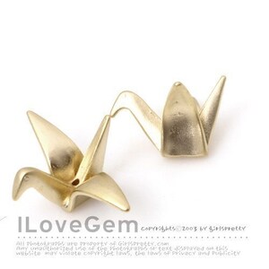 May include: Two gold-colored metal crane charms shaped like origami birds. Each crane features a pointed beak, wings extended outward, and a small hole at the center of the back. The text ILoveGem is printed in the lower left corner of the image.