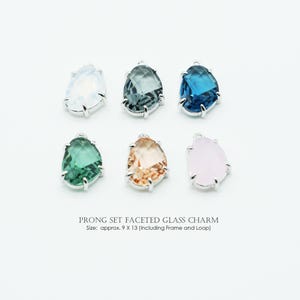 May include: Six faceted glass charms in assorted colors: white, grey, blue, green, peach, and pink. Each charm features a silver-toned prong setting and a loop. The text reads "PRONG SET FACETED GLASS CHARM" and the size is approximately 9 x 13 mm.