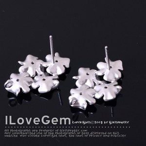 May include: A pair of silver-toned stud earrings, each featuring a cluster of four-leaf clover shapes. The earrings have a metallic finish and include a post backing. The text ILoveGem and copyright information are visible at the bottom.