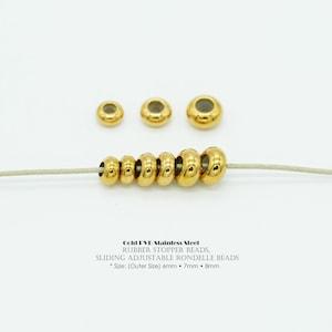 May include: A collection of gold-colored stainless steel rondelle beads in various sizes, strung on a light-colored cord. The beads are round with a flat surface and a hole through the center. The sizes are 6mm, 7mm, and 8mm.