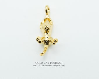 May include: A gold-colored cat pendant with a loop for hanging. The pendant is in the shape of a cat with its paws outstretched. The text "GOLD CAT PENDANT" is below the pendant, with the size listed as 7.5 x 19 mm.
