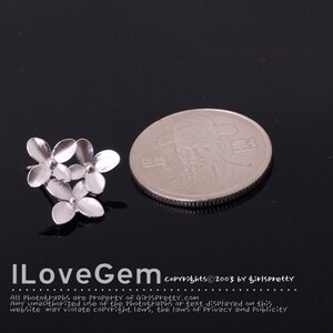 May include: Silver flower earrings with a cluster of five small flowers. The earrings are shown next to a South Korean Won coin for size comparison.