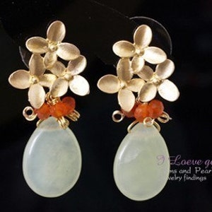 May include: A pair of dangle earrings with a light green stone drop, gold flower accents, and orange beads.