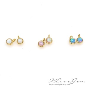 Puede incluir: Seis abalorios dorados con piedras de ópalo. Los abalorios son redondos y tienen un borde de cuentas. Los ópalos son de tres colores: blanco, rosa y azul.