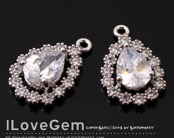 May include: Two silver teardrop-shaped earring charms with clear crystal stones set in a halo of smaller stones. The charms have a loop at the top for attaching to earrings.
