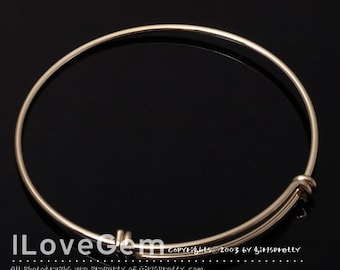 May include: A gold bangle bracelet with a simple design. The bracelet is open and has a clasp on one side.