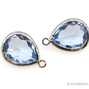 May include: Two light blue teardrop-shaped glass pendants with silver settings and a silver loop for hanging.