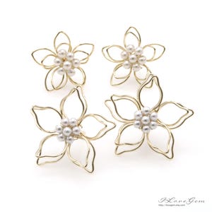 Peut inclure: Boucles d'oreilles en fil d'or avec un délicat motif de fleur et des accents de perles blanches.