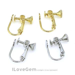 Könnte beinhalten: Zwei Paar Ohrclips, ein Paar ist golden und das andere silbern. Beide Paare haben ein Schraubdesign.