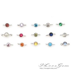 May include: Assortment of 15 silver-toned connector charms with various coloured gemstones. Each charm features a round gemstone surrounded by a decorative border. The gemstones include red, pink, blue, green, yellow, white, and turquoise.