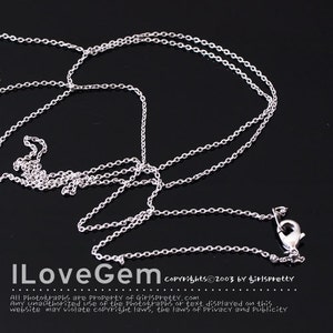 May include: A silver-colored necklace with a delicate chain and a lobster clasp. The necklace is displayed against a dark background. The text "ILoveGem" and copyright information are visible at the bottom of the image.