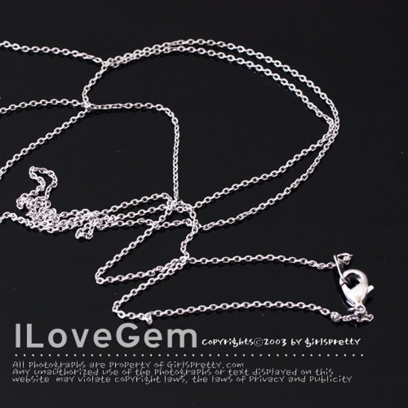 May include: A silver-colored necklace with a delicate chain and a lobster clasp. The necklace is displayed against a dark background. The text "ILoveGem" and copyright information are visible at the bottom of the image.