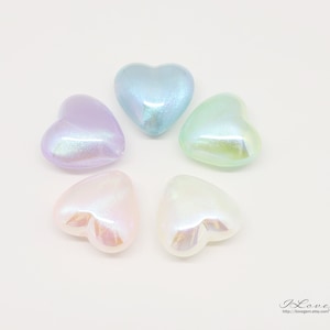 Puede incluir: Seis cuentas iridiscentes en forma de corazón en varios colores pastel, incluyendo azul claro, lavanda, verde y rosa.