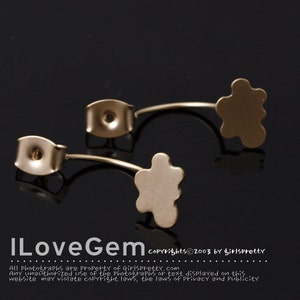May include: A pair of gold-toned earring backs with a flower-shaped design. The backs are designed to be used with stud earrings.
