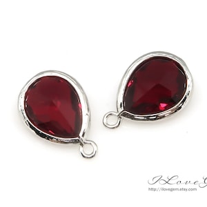 Pode incluir: Dois pingentes de prata em forma de lágrima com detalhes em cristal vermelho. Os pingentes têm um laço na parte superior para prender a uma corrente ou outras joias.