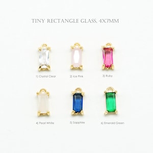 May include: Six tiny rectangle glass charms in various colors, each measuring 4x7mm, with gold-colored metal settings. Colors include crystal clear, ice pink, ruby, pearl white, sapphire, and emerald green. The text "TINY RECTANGLE GLASS, 4X7MM" is at the top.