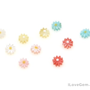 May include: Assortment of colourful flower-shaped buttons with a pearl-like finish. The buttons are in shades of pink, blue, yellow, and white.