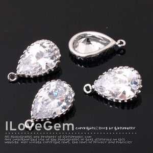 May include: Four silver teardrop-shaped charms with clear crystal stones. Each charm has a small loop at the top for attaching to jewelry.