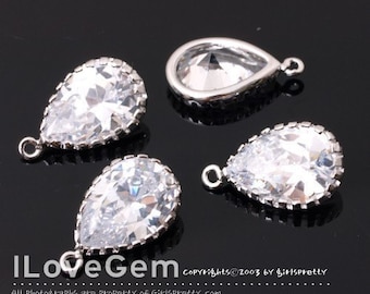 May include: Four silver teardrop-shaped charms with clear crystal stones. Each charm has a small loop at the top for attaching to jewelry.