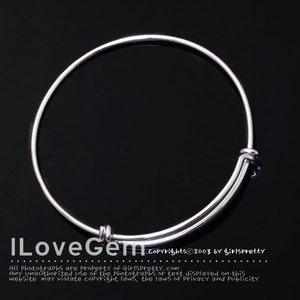 May include: A silver bangle bracelet with a simple design. The bracelet is open and has a hinged clasp.