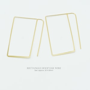 May include: Two gold-colored rectangle hoop earrings. The earrings are made of thin wire and have a minimalist design. The text "RECTANGLE HOOP EAR WIRE" is below the earrings. Size: approx. 1.4 x 2 inches.