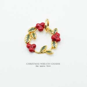 May include: A gold-colored Christmas wreath charm with red berries and green leaves. The charm is approximately 0.5 inches in diameter. The text "CHRISTMAS WREATH CHARM" is below the charm.