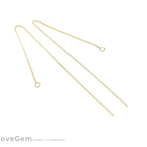 May include: A pair of gold dangle earrings with a thin chain and a straight, long, gold bar.