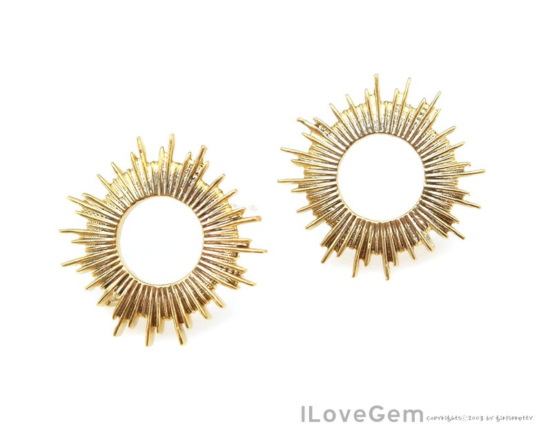 K&ouml;nnte beinhalten: Ein Paar goldene Sonnenstrahlen-Ohrringe mit einem runden Design. Die Ohrringe sind aus Metall und haben eine gl&auml;nzende Oberfl&auml;che.