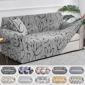 May include: A grey sofa cover with a black floral design is draped over a white sofa. A matching cushion is on the sofa. The cover is being adjusted by a hand. Several other sofa cover designs are shown below.