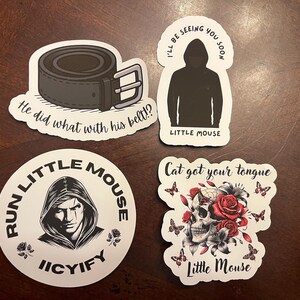 May include: Four stickers with black and white illustrations and text. The first sticker features a black leather belt with the text "He did what with his belt!?". The second sticker features a hooded figure with the text "I'll be seeing you soon" and "Little Mouse". The third sticker features a hooded figure with the text "Run Little Mouse Icyify". The fourth sticker features a skull with flowers and the text "Cat got your tongue" and "Little Mouse".
