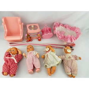 May include: A collection of vintage baby dolls and accessories in shades of pink. Includes dolls in pajamas, a high chair, a swing, a bassinet, and other toys. The dolls have painted features and are wearing pacifiers.