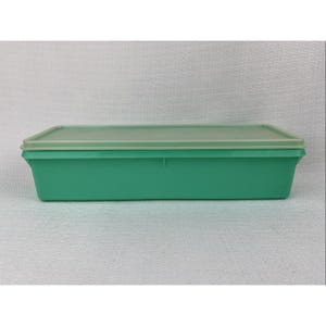 May include: A rectangular, teal-colored plastic container with a light green lid. The container has a simple, classic design, suitable for food storage. The lid fits snugly on top, creating a secure seal. The container is made of durable plastic.
