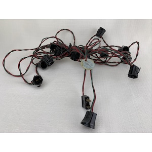 May include: A tangled string of Christmas lights with black sockets and red and green wiring. The string has a UL label and a two-prong plug. The lights are designed for indoor use.