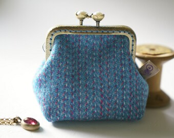 May include: A small blue coin purse with a gold metal frame and a pink and white patterned fabric. The purse has a clasp closure.