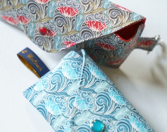 May include: Two fabric pouches with floral patterns. The larger pouch has a red floral pattern on a blue background. The smaller pouch has a blue and white floral pattern. Both pouches have a button closure.