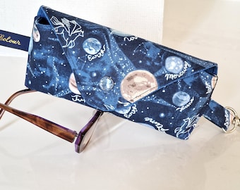 May include: A blue fabric glasses case with a celestial print featuring planets, stars, and a winged horse. The case has a strap with a metal clasp.