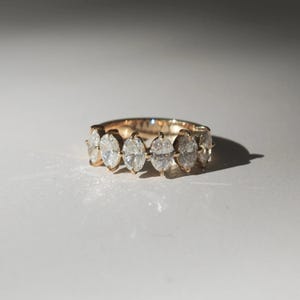 May include: A gold band ring with a row of oval-shaped diamonds.