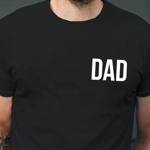 May include: A black t-shirt with the word "DAD" printed in white on the front.