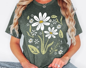 May include: Heather forest green t-shirt with a daisy floral design. The graphic features white daisies with yellow centers and green leaves and stems. The text "HEATHER FOREST GREEN" is at the top left.