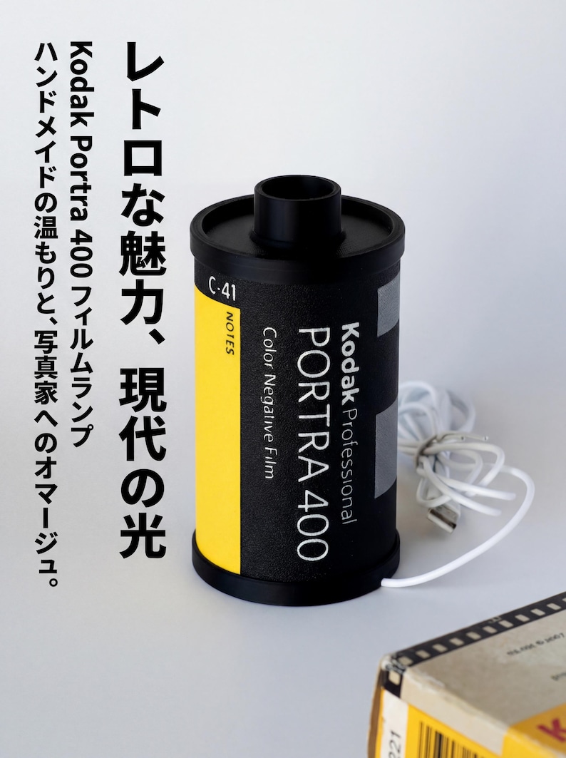 May include: A black Kodak Portra 400 film lamp with a yellow stripe and white cord. The lamp has text in Japanese and English. The lamp is a handmade homage to photographers.