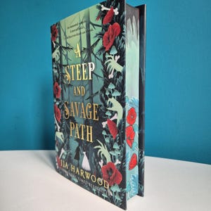 Peut inclure: Livre "A Steep and Savage Path" de Jia Harwood. La couverture présente un motif de forêt sombre avec des fleurs rouges, des os et du feuillage vert. Le titre est en lettres dorées. Le livre est un best-seller du Sunday Times.