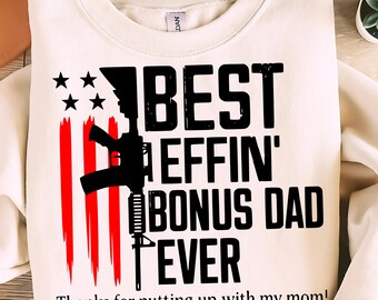 May include: Cream-colored sweatshirt with the text "BEST EFFIN' BONUS DAD EVER" in black, along with a graphic of a rifle and an American flag design. The text "Thanks for putting up with my mom!" is printed below.