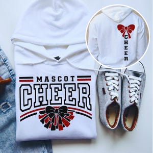 May include: White hooded sweatshirt with the text "MASCOT CHEER" in black and red. A black and red bow graphic is below the text. The back of the sweatshirt has a red bow graphic and the word "CHEER" vertically.