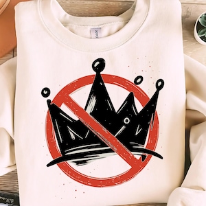 Könnte beinhalten: Cremefarbenes Sweatshirt mit einem schwarzen Kronen-Design, das von einem roten Kreis und Schrägstrich durchgestrichen ist. Die Grafik hat eine verwaschene, handgezeichnete Ästhetik. Das Rundhals-Sweatshirt ist aus weichem Material.