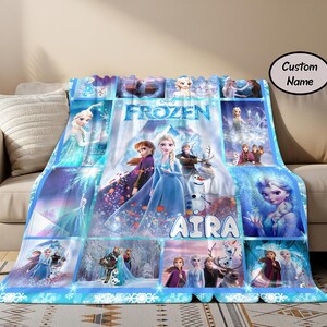 以下が含まれることがあります： エルサ、アナ、オラフをフィーチャーした、青と白のフローズンをテーマにしたブランケット。 ブランケットには「FROZEN」の文字と「AIRA」の名前がプリントされたコラージュデザインが施されています。 ブランケットはベージュのソファに掛けられています。