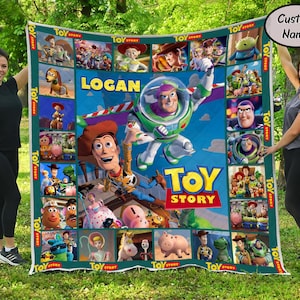 Puede incluir: Una colorida manta con temática de Toy Story que presenta varios personajes de la película animada. La manta tiene un fondo azul con imágenes de Woody, Buzz Lightyear y otros personajes. El nombre "LOGAN" se muestra de forma destacada.