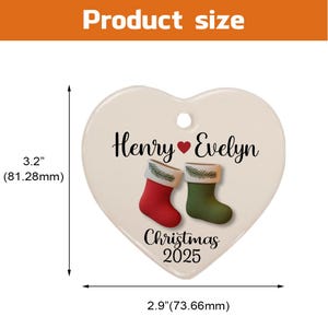 May include: Heart-shaped Christmas ornament, 3.2 inches (81.28mm) tall and 2.9 inches (73.66mm) wide. Features the names "Henry" and "Evelyn" with a heart symbol, and two Christmas stockings. The text "Christmas 2025" is also included.