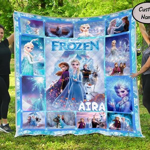 以下が含まれることがあります： ディズニー映画「アナと雪の女王」のシーンとキャラクターが描かれた、長方形の大きなキルト。キルトは青と白を基調とし、エルサ、アナ、オラフなどのキャラクターの画像が描かれています。「Aira」という名前がキルトにプリントされています。