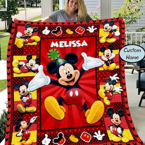 Puede incluir: Una manta roja y negra con el tema de Mickey Mouse. La manta presenta m&uacute;ltiples im&aacute;genes de Mickey Mouse en varias poses, con el nombre "MELISSA" en letras blancas. El borde tiene iconos de Mickey Mouse y una opci&oacute;n de "Nombre personalizado".