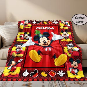Puede incluir: Una manta roja, negra y amarilla con el tema de Mickey Mouse. La manta presenta una imagen grande de Mickey Mouse con el nombre "Melissa" y varias im&aacute;genes m&aacute;s peque&ntilde;as de Mickey Mouse. La manta est&aacute; sobre un sof&aacute; beige.